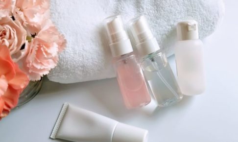カーネーションとタオルと一緒に置かれている化粧品のミニボトル