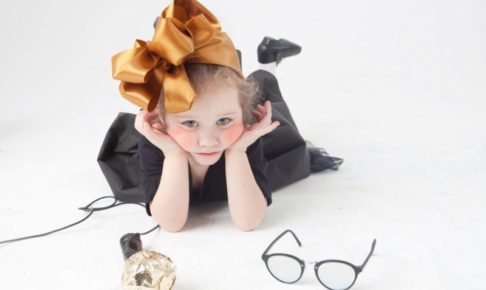 頭に大きなリボンを付けた両肘をついてこちらを見る黒服の幼女