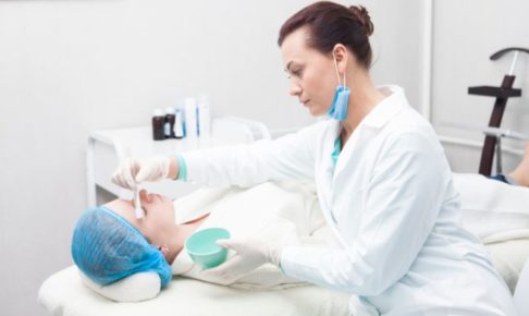 整形外科医と何かを塗られている白人女性