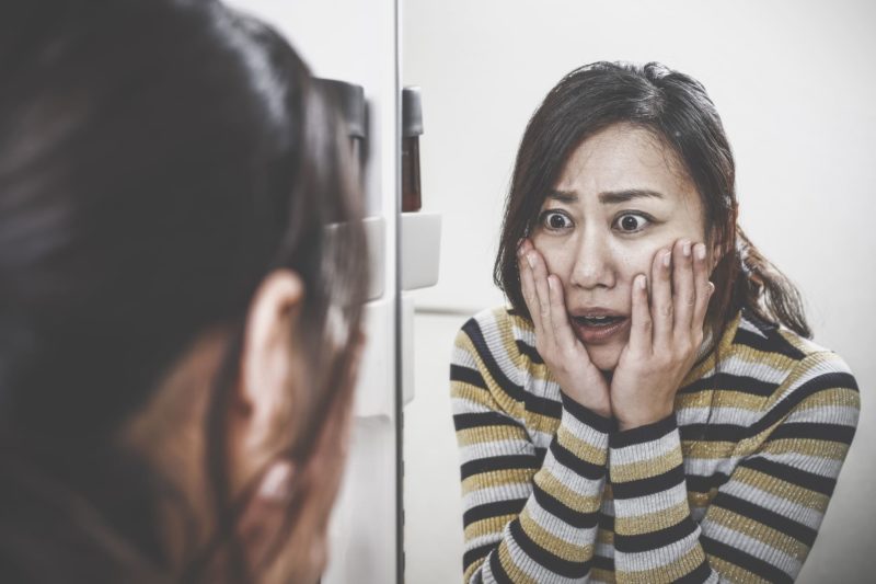 鏡を見てとてもショックを受けている日本人女性