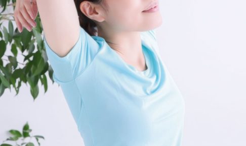 大きく伸びをしている水色Tシャツを着た女性の脇