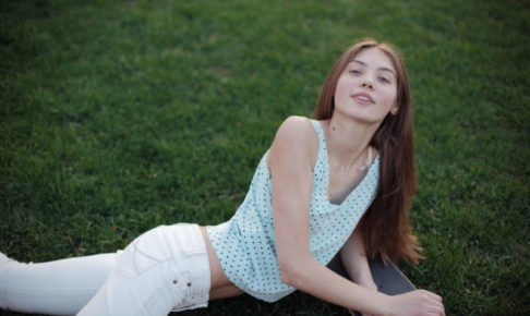 芝生にローラーブレードの上で寝そべってポーズしている女性