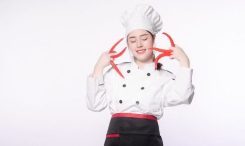 赤トウガラシを何本も持ってポーズを決めている女シェフ