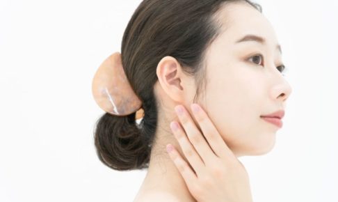 首に逆手を添えている女性