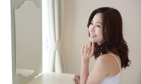 鏡をみてにっこり微笑む女性