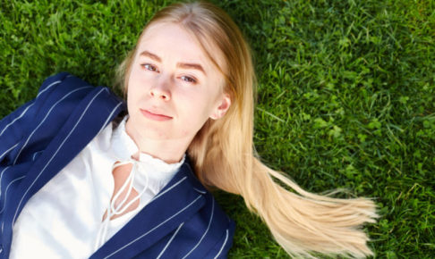 芝生に寝そべってキリッとした表情を見せる女の子