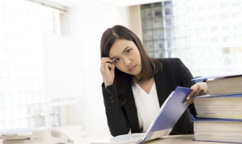 仕事のストレスで頭を抱えているアジア女性