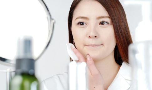 鏡を見ながらコットンでスキンケアする女性