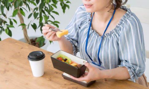 自分で作ったお弁当を食べる青いブラウスの女性