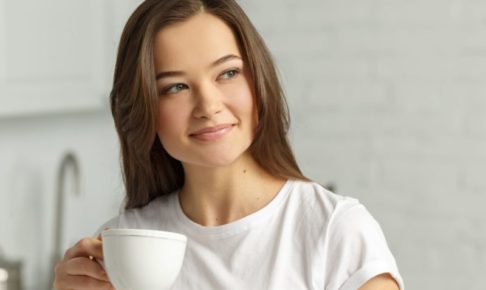 白いカップを持ってリラックスしている女性のアップ