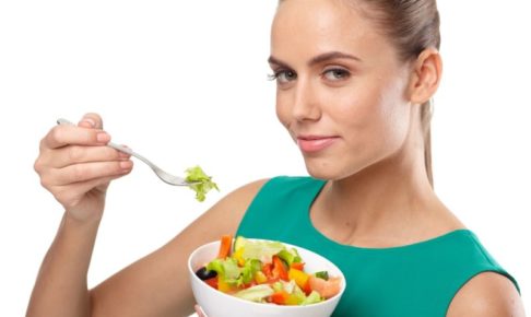 サラダボウルを食べる緑の服の白人女性