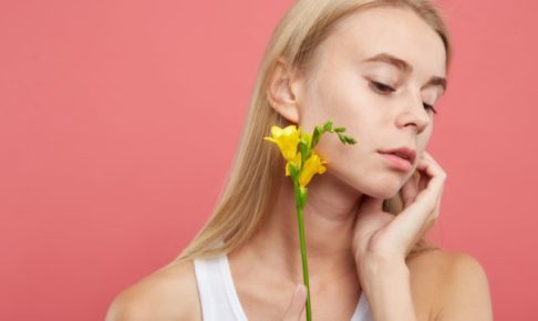 ピンクの背景に黄色い花を持って横を向いている女の子