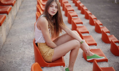 オレンジのスタジアムの席で座っている外国人女性