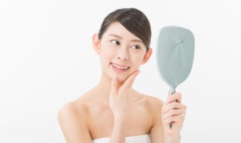 手鏡を見て笑顔を浮かべている女性