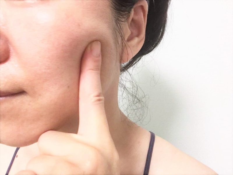 咬筋のだいたいの位置を指差す女性