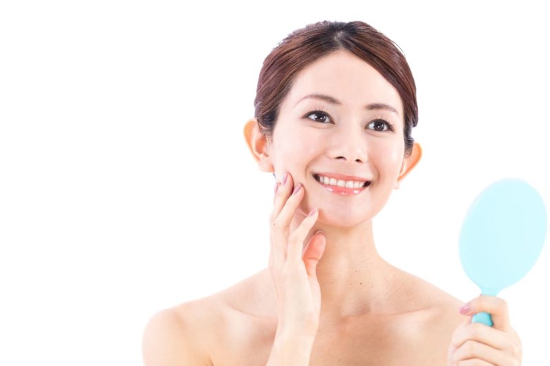 青い鏡を見て晴々している女の人