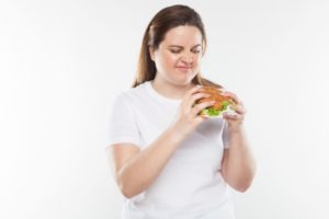 ハンバーガーを持って食べようとしている太めの女性