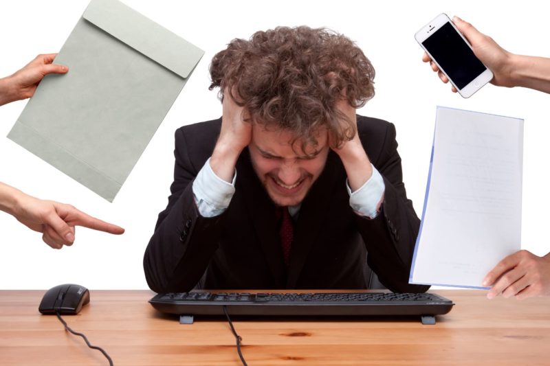 数々の仕事を要求されてストレスになっている男性