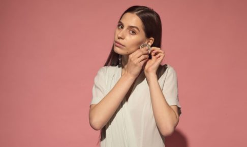 ピンク背景に左耳に大きなピアスをした女の人