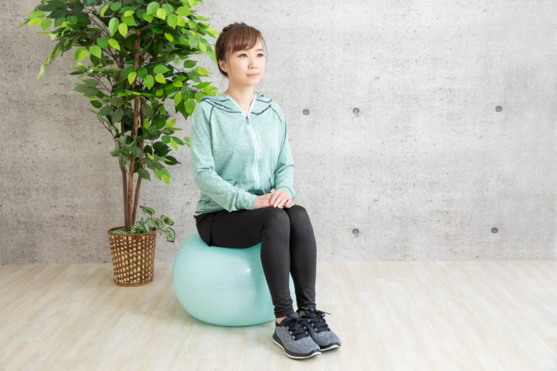 バランスボールの上に座って体幹を鍛えている女性
