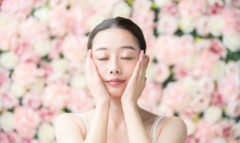 バラに囲まれ手を頬に持っていってうっとりしている女性