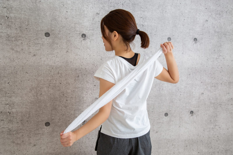 タオルで背中をトレーニングしている女性の後ろ姿