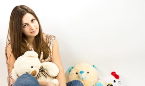 ぬいぐるみを抱きながらしかめっ面をしている女性