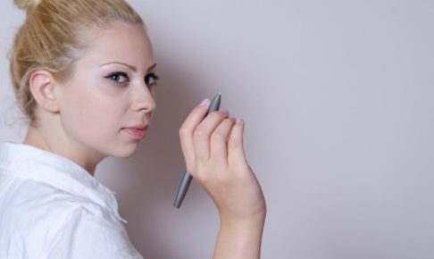 後ろの壁に何か特殊なペンで書こうとしている女性