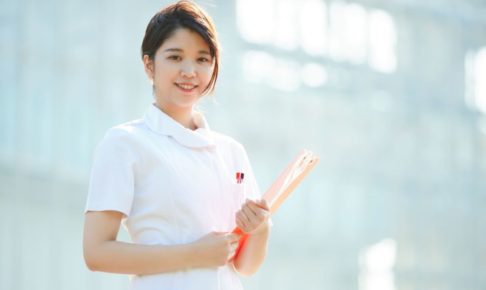 日の当たる背景の中で微笑む若い看護師