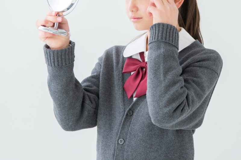 頬のあたりを気にする女子学生
