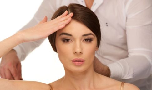 後ろの人に施術されながらおでこを気にする婦人