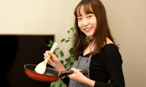 黒いエプロンをしてこれから調理を始めようとする女子