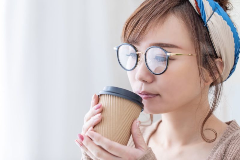 丸い眼鏡をして穏やかにカフェしている女性