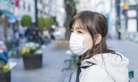 街中でマスクをしている冬服の女性