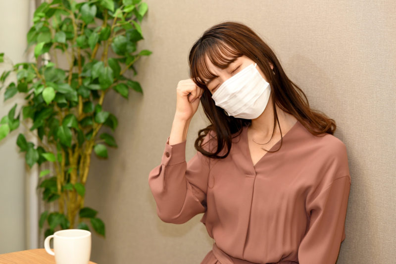 オフィスでマスクをして苦しそうにしている女性