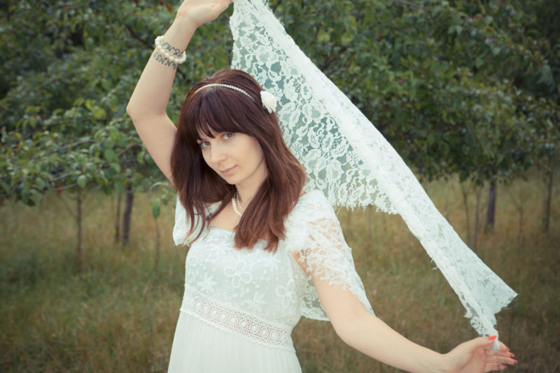 ウェディングドレスを着てレースショールを上げている女性