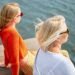 海沿いに座り景色を眺めている女性二人の後頭部