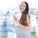 日の当たるベランダで水を持って微笑んでいる妊婦