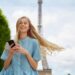 エッフェル塔か高い塔の下でスマホをいじっている青ワンピースの女性