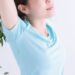 大きく伸びをしている水色Tシャツを着た女性の脇