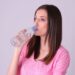 水をごくごく飲んでいるピンクの服着た女性