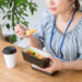 自分で作ったお弁当を食べる青いブラウスの女性