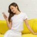 黄色いソファとクッションでスマホをいじっている女性