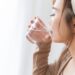 コップ1杯の水を光が差し込むところで飲む女性の横顔