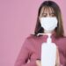 紫の背景の前で消毒薬を持っている女性